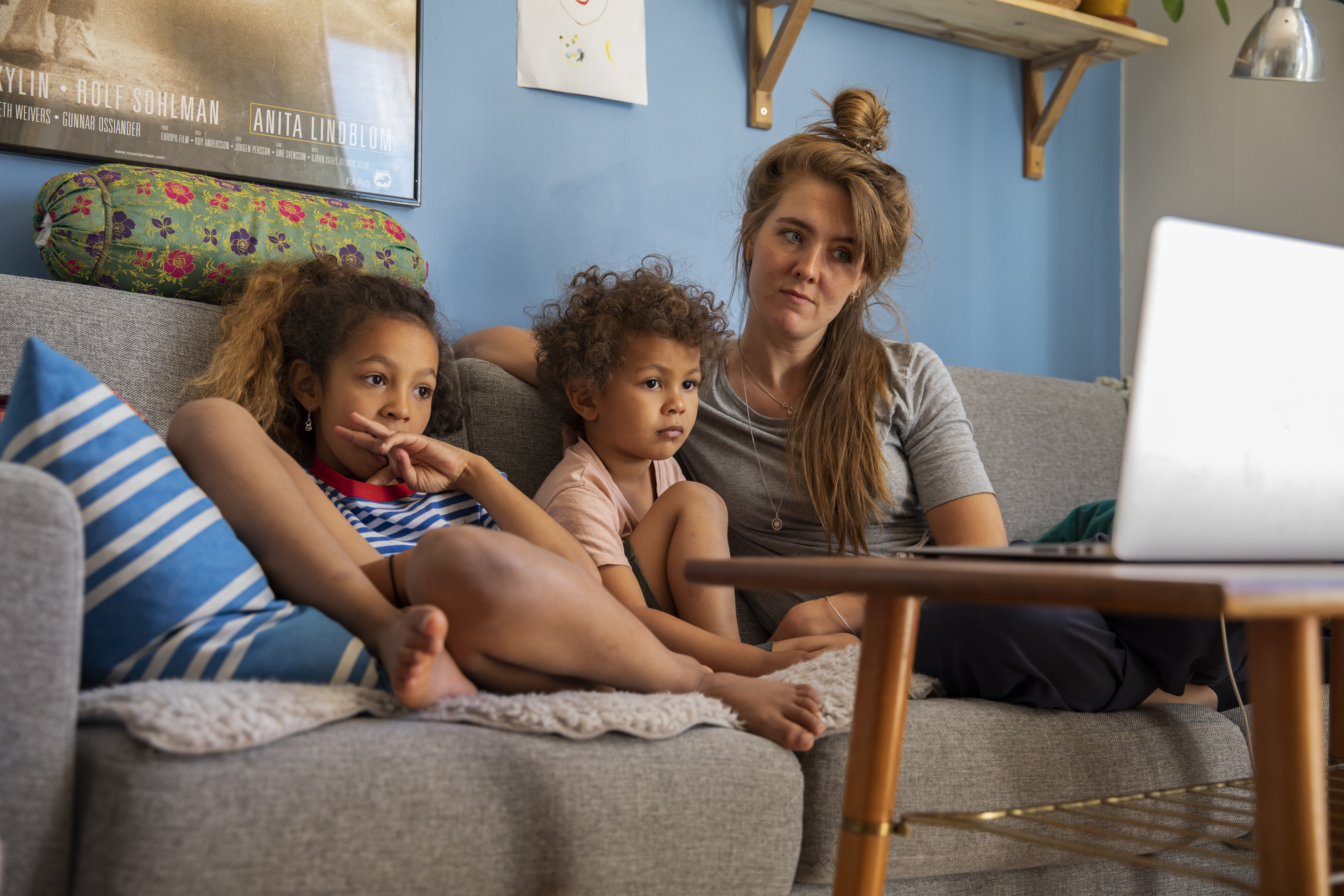 En vuxen sitter med två barn i en soffa.