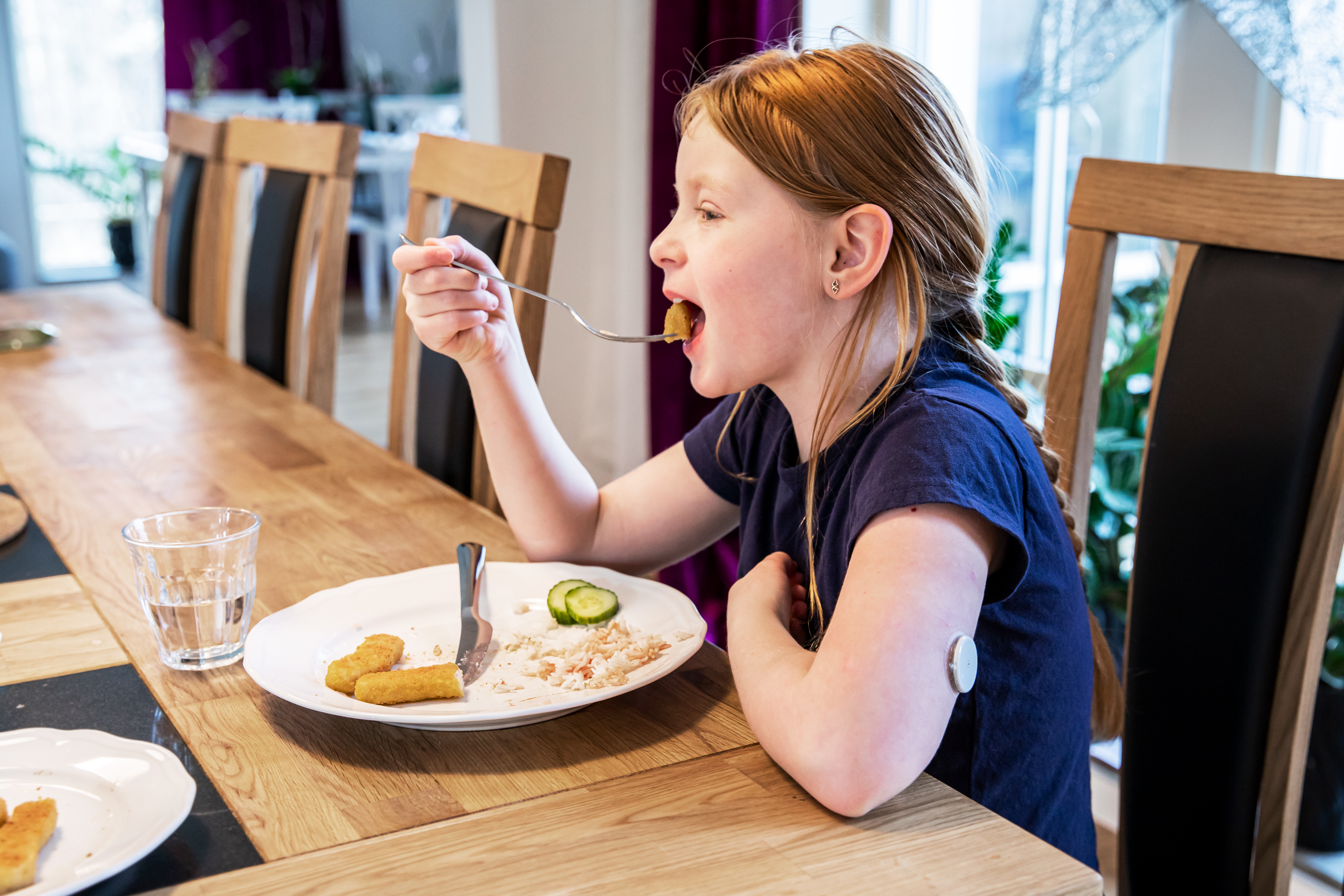 Ett barn som sitter vid ett bord och äter.