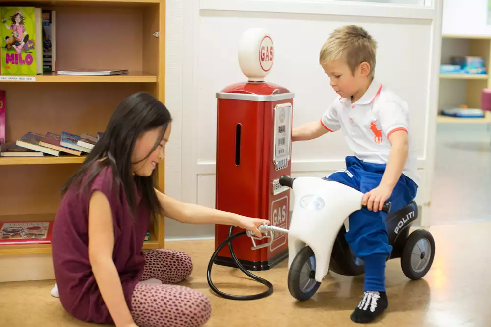 Två barn leker att de tankar en leksaksmotorcykel på sjukhus.