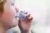 Ett barn dricker ur en liten mugg.