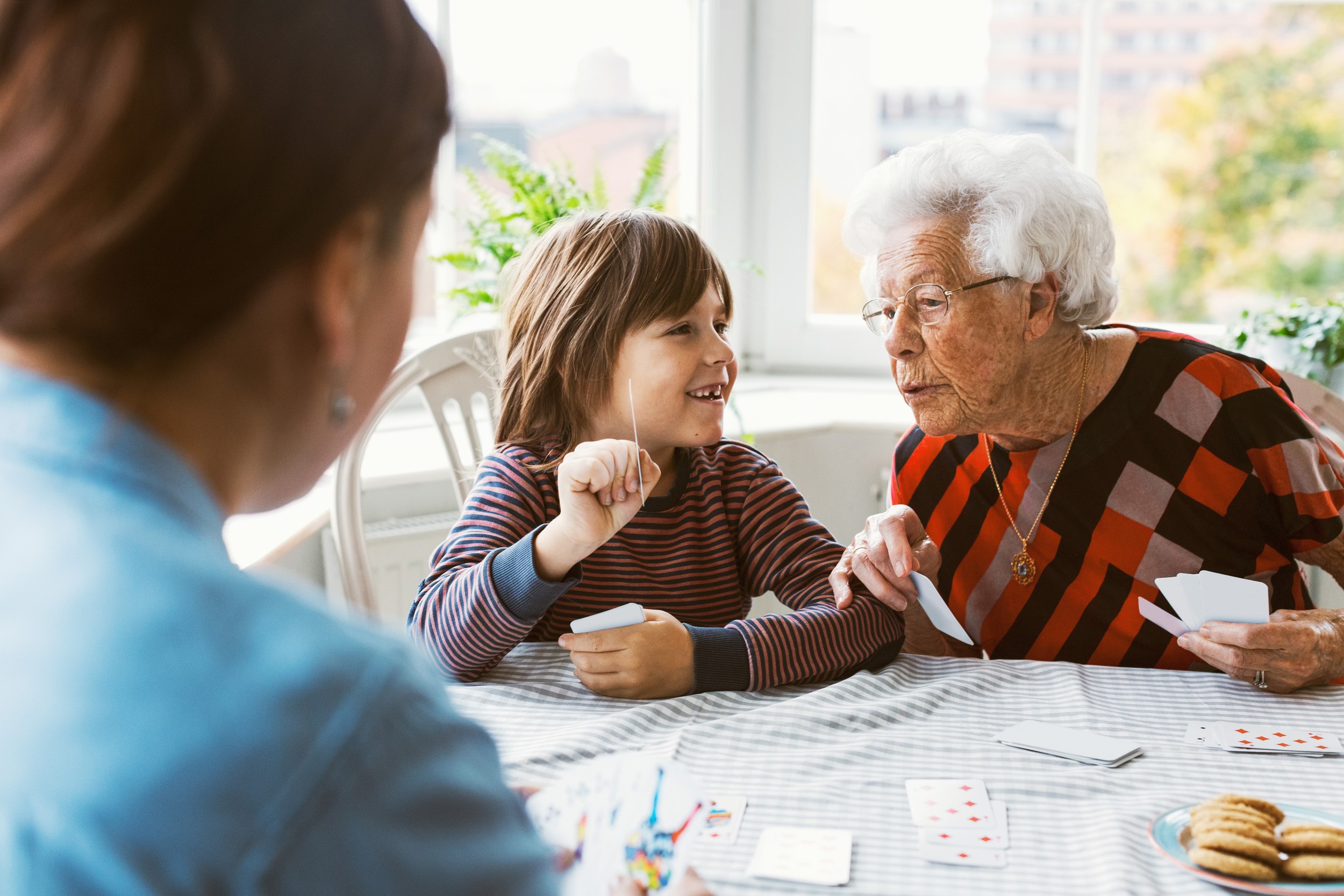 En äldre dam spelar kort tillsammans med ett barn.