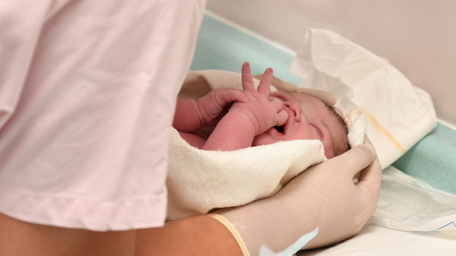 Nyfödd med vårdpersonal som håller om barnet i en filt