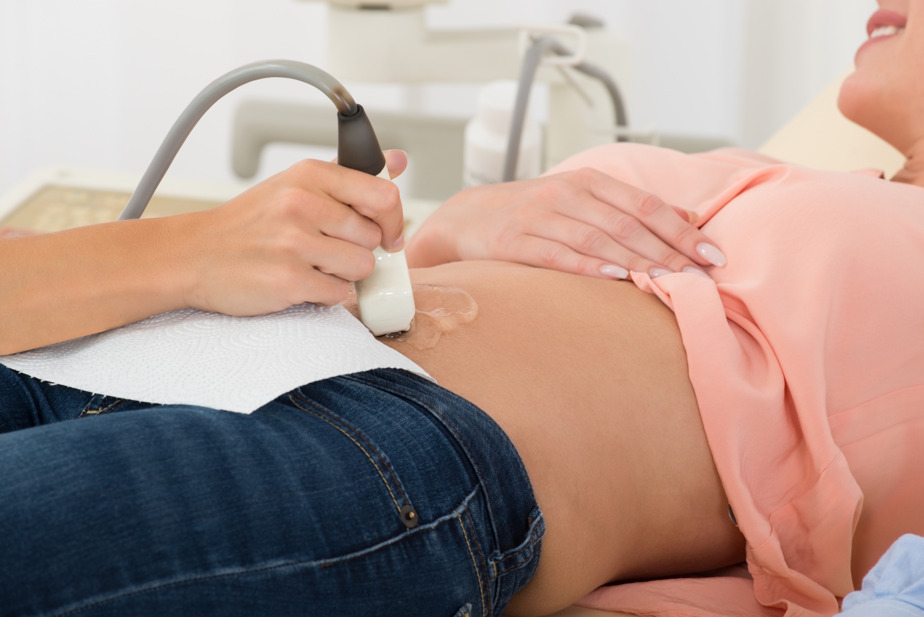 Doktor flyttar ultraljudsscannerinstrument över gravid kvinnas mage