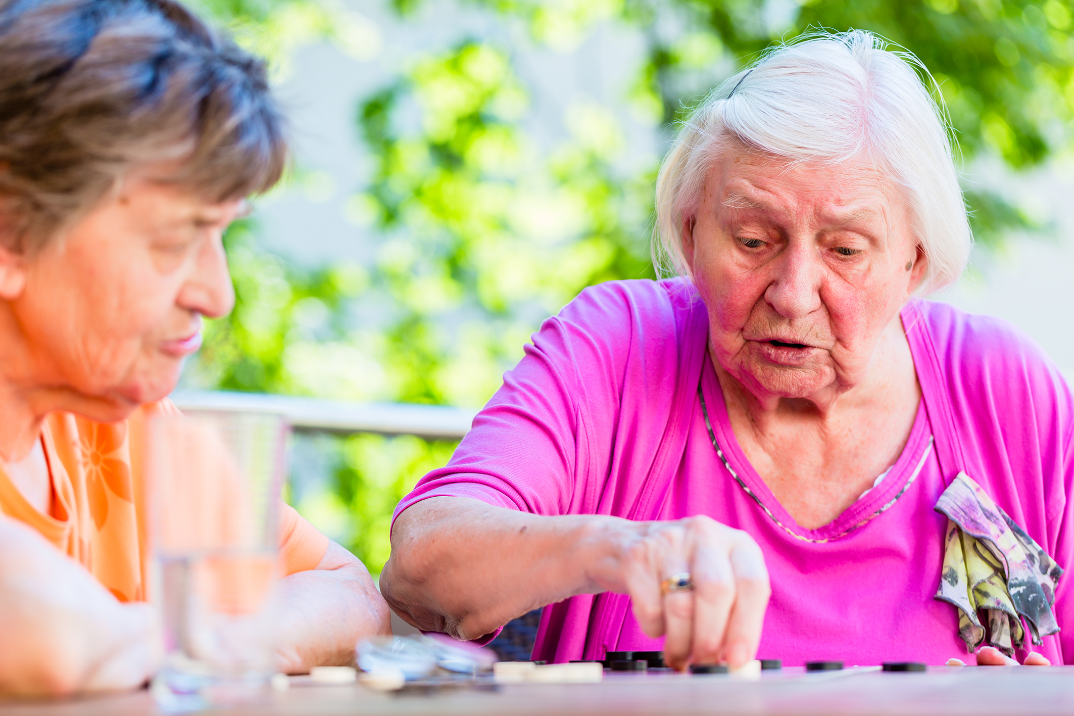 Två äldre damer spelar brädspel i solen