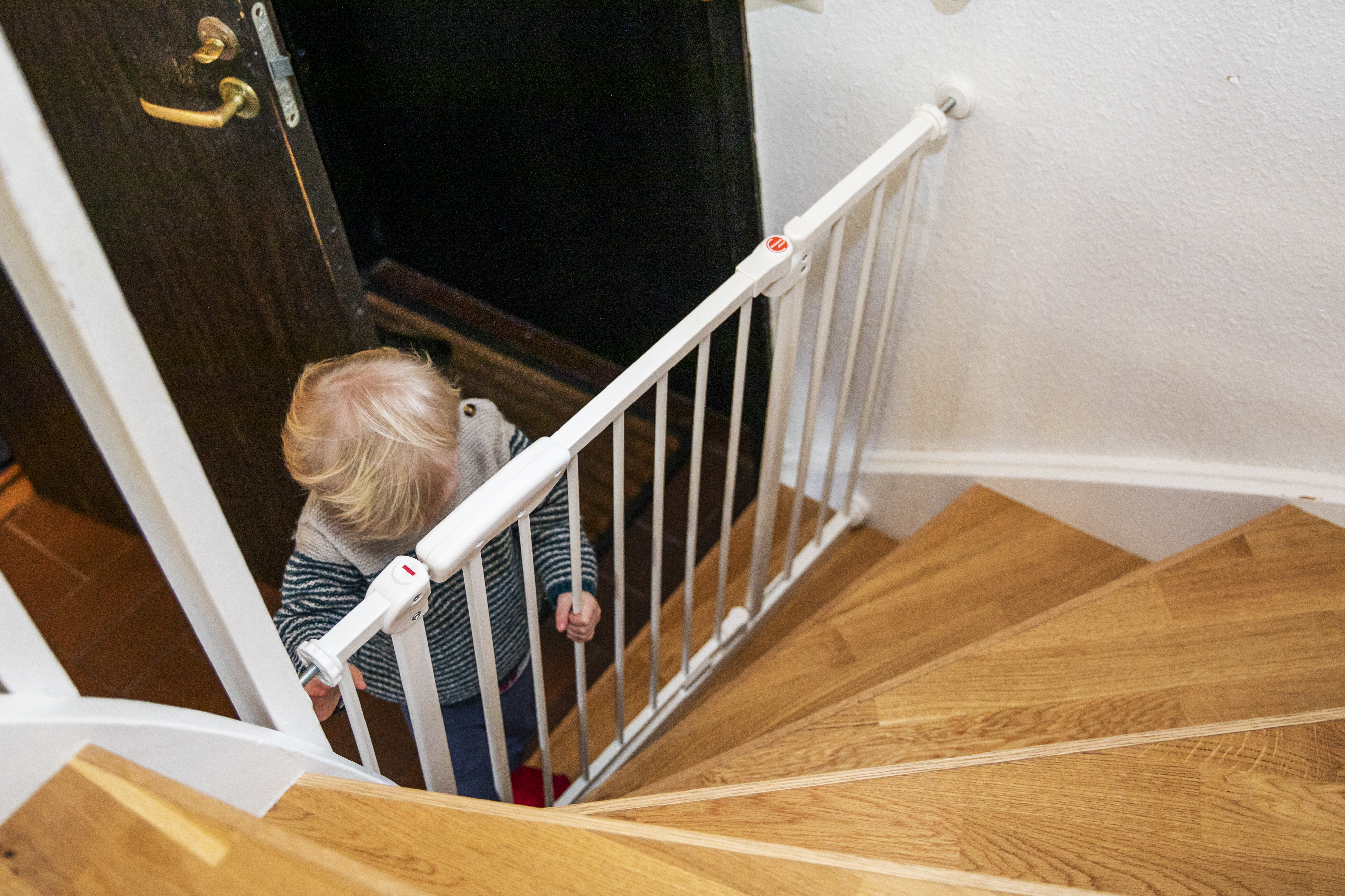 Ett barn som står vid en säkerhetsgrind vid en trappa.