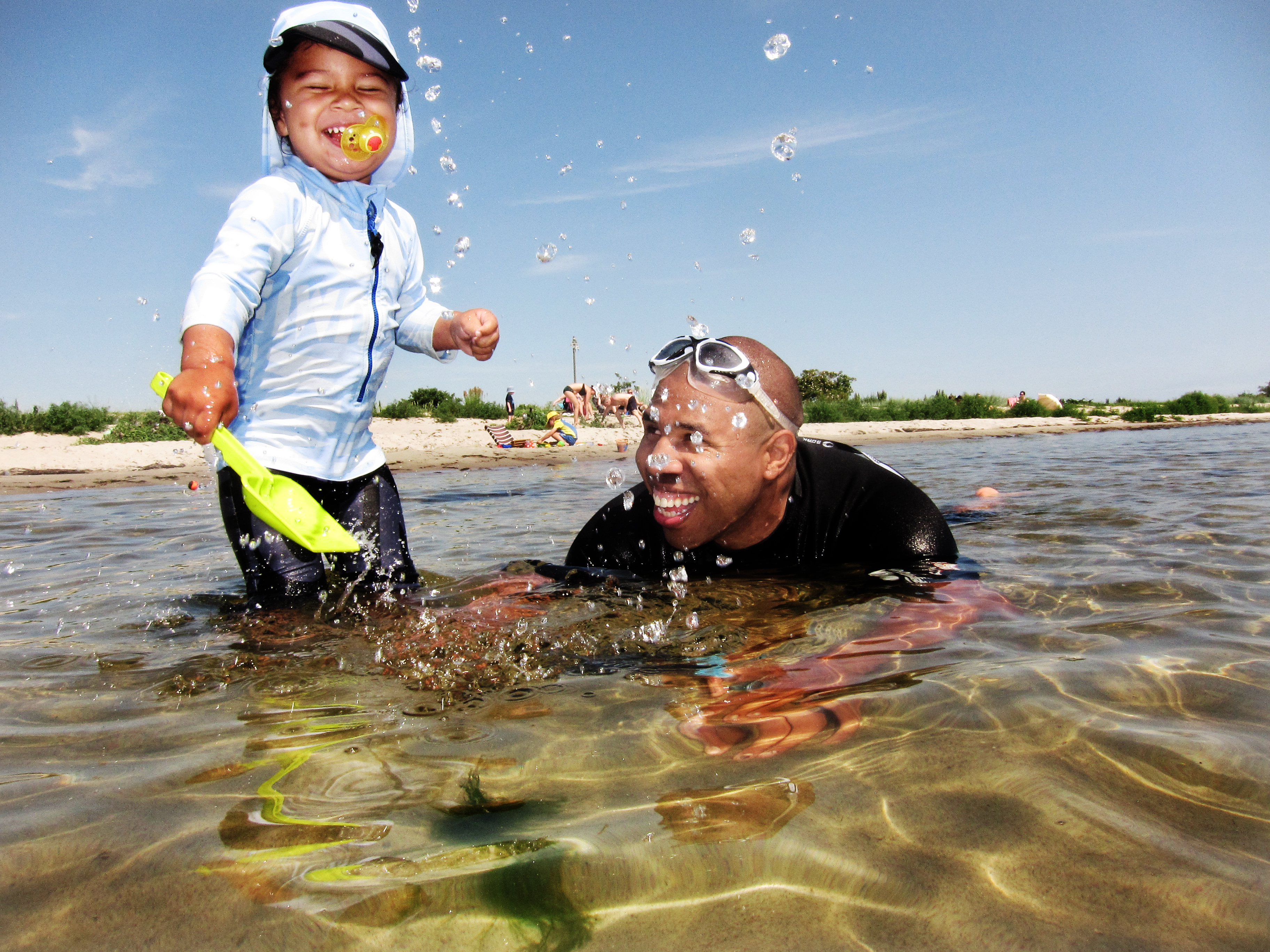 En man och ett barn leker i vattnet.