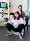 Gravid kvinna i ställning för att föda på huk, med sin partner bakom sig.