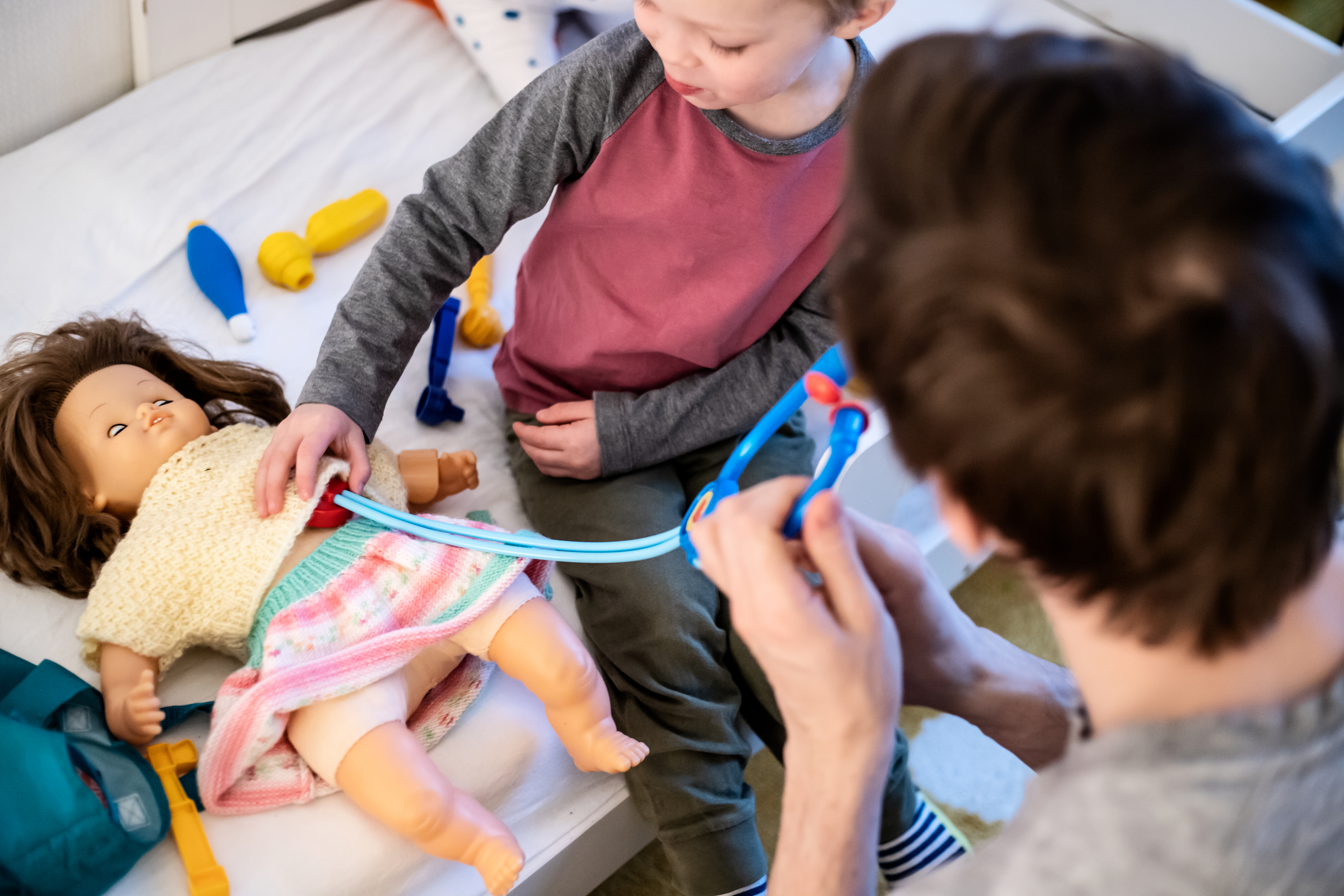 Ett barn och en vuxen leker sjukvård med en docka.