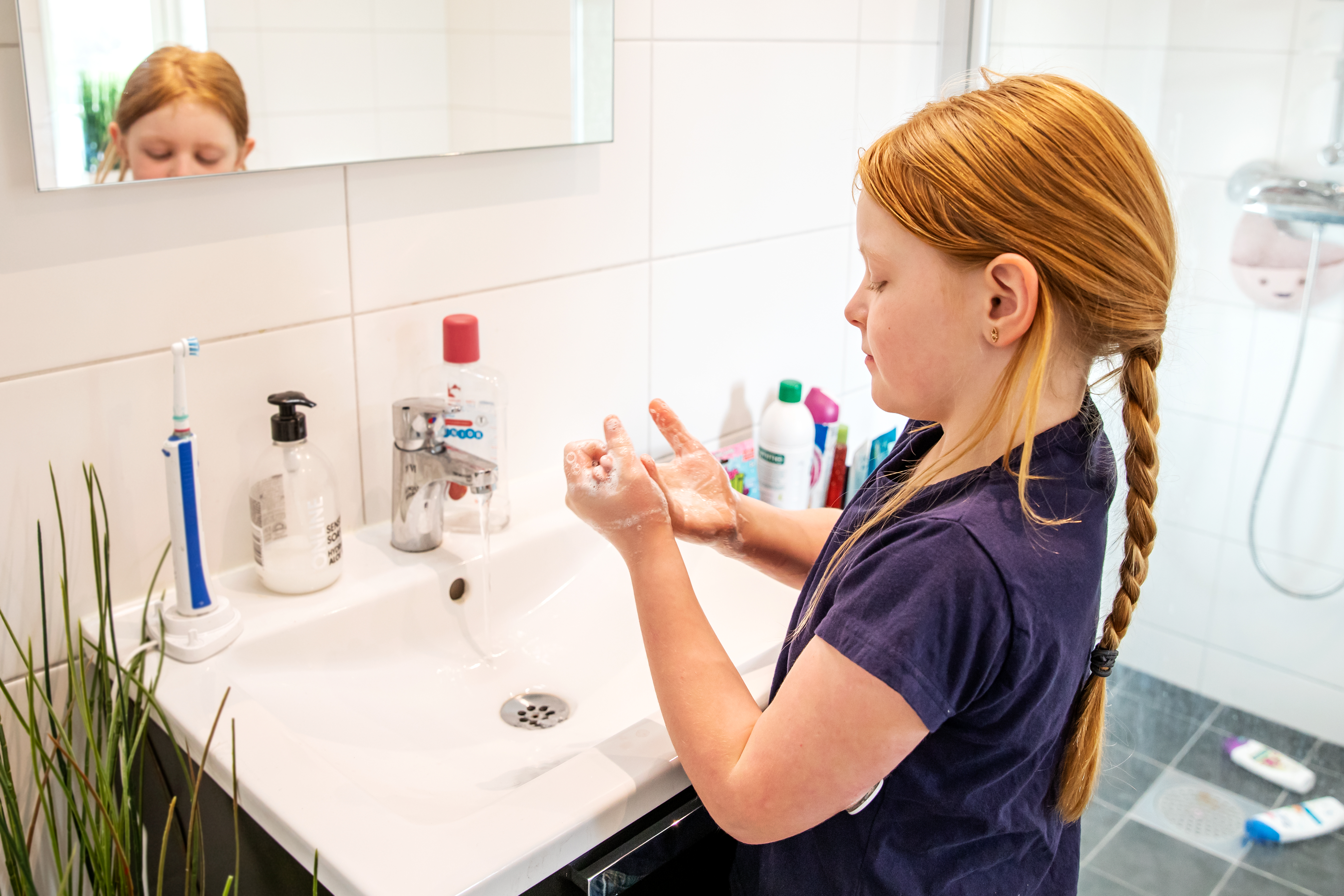 Ett barn tvättar händerna med mycket skum. Fotografi. 