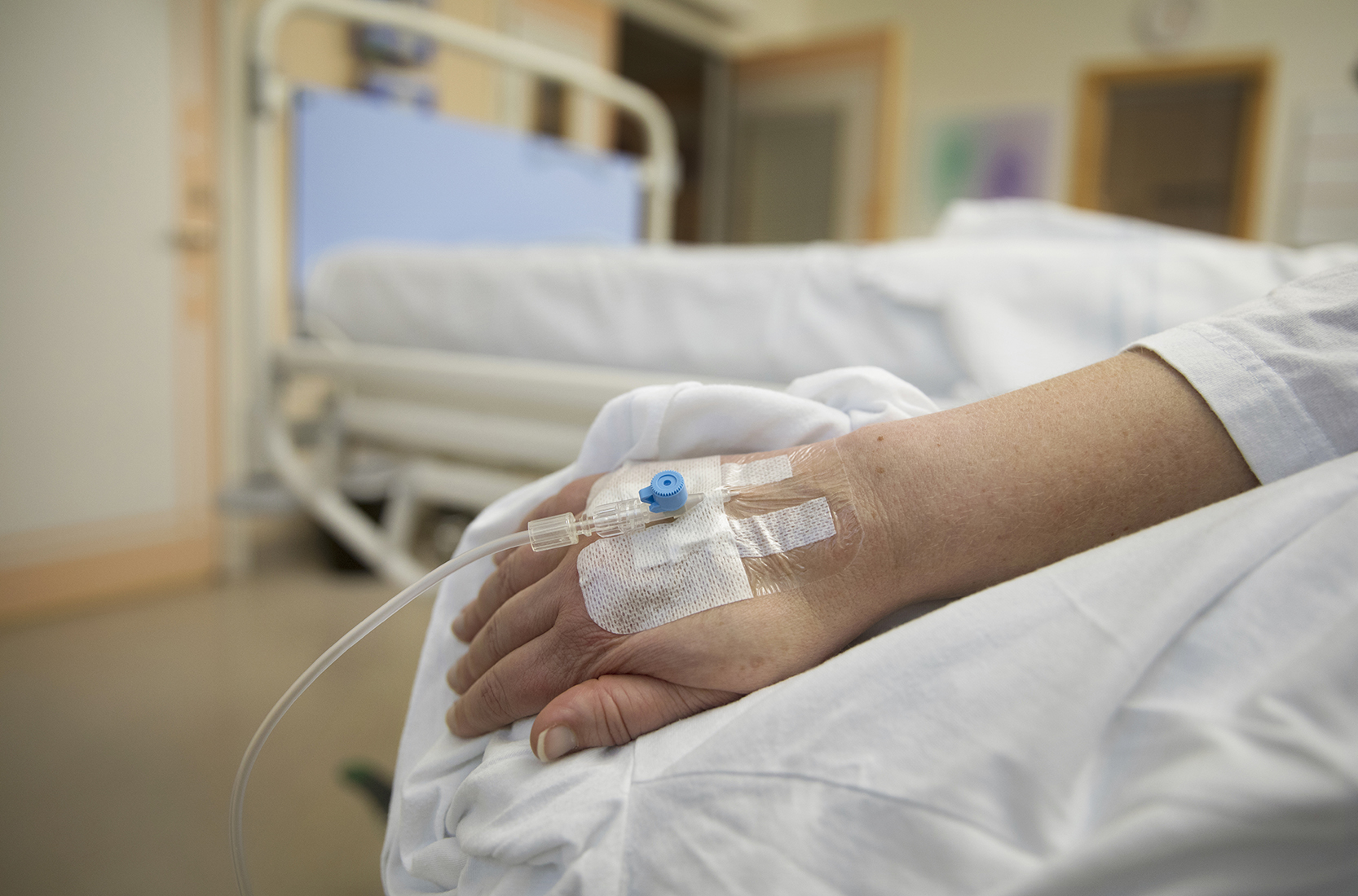 Venkateter som är fäst på handryggen med ett genomskinligt förband. Fotografi.