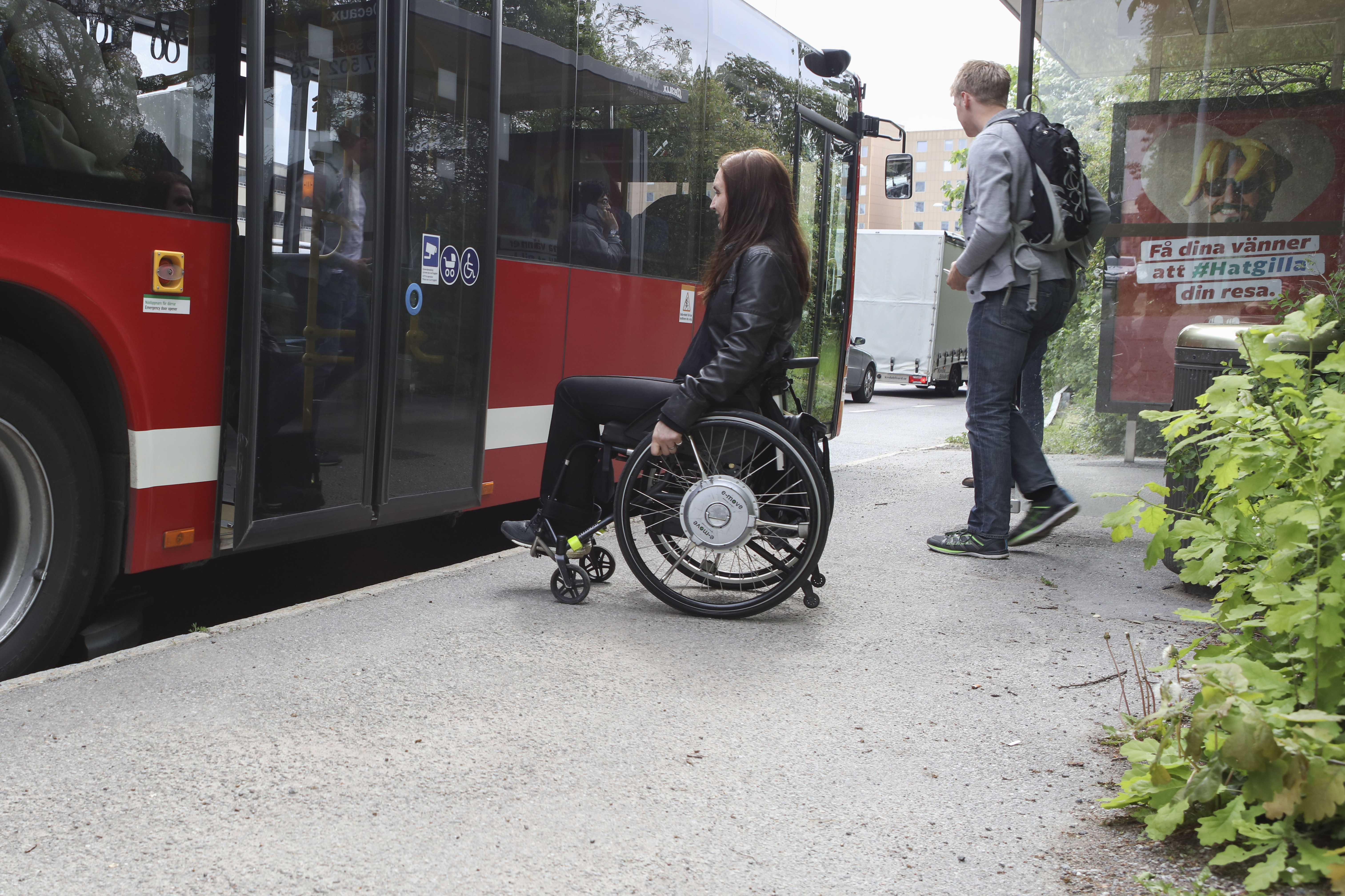 Person i elrullstol framför dörren på en buss. Fotografi.