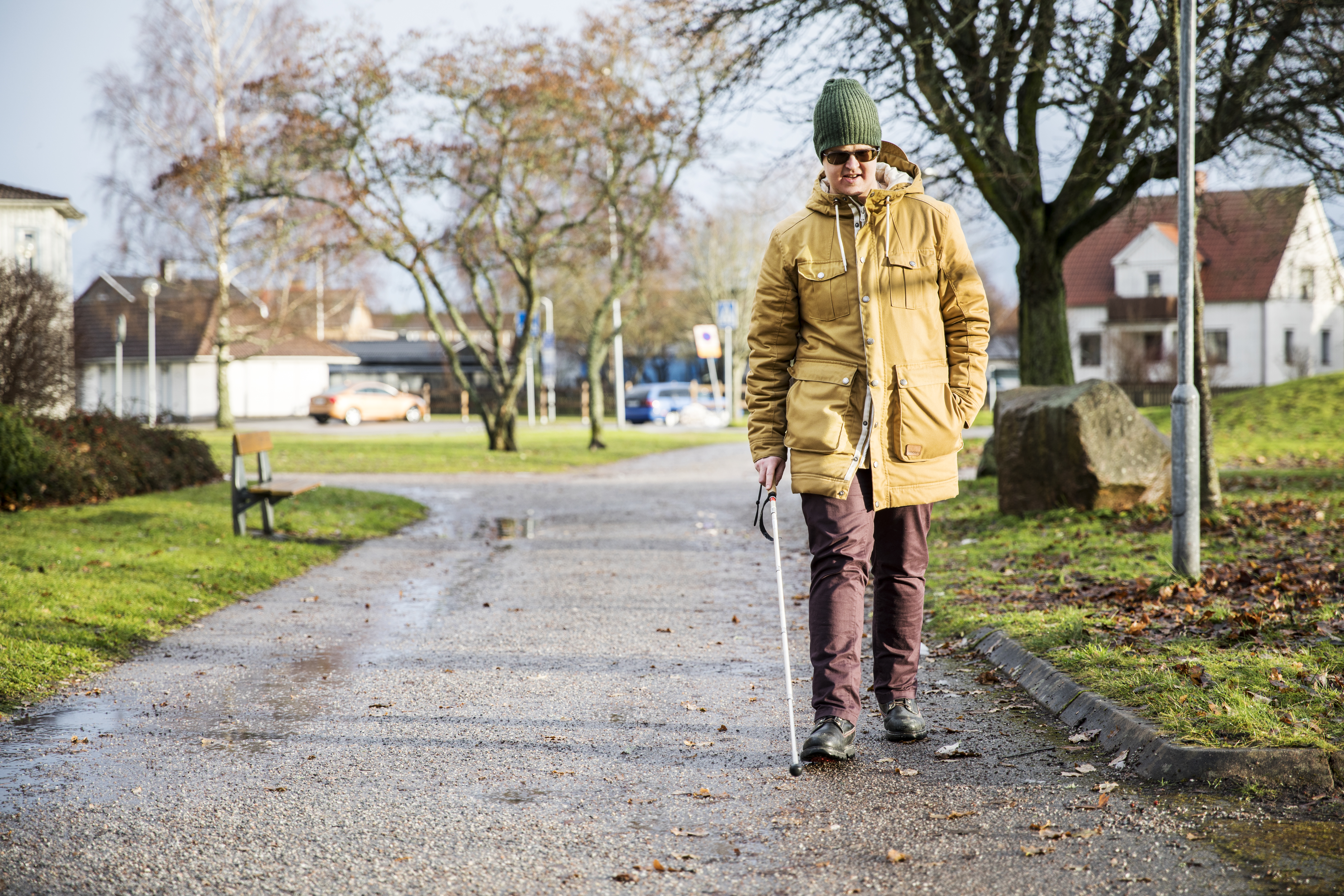 En person går utomhus med en vit käpp.