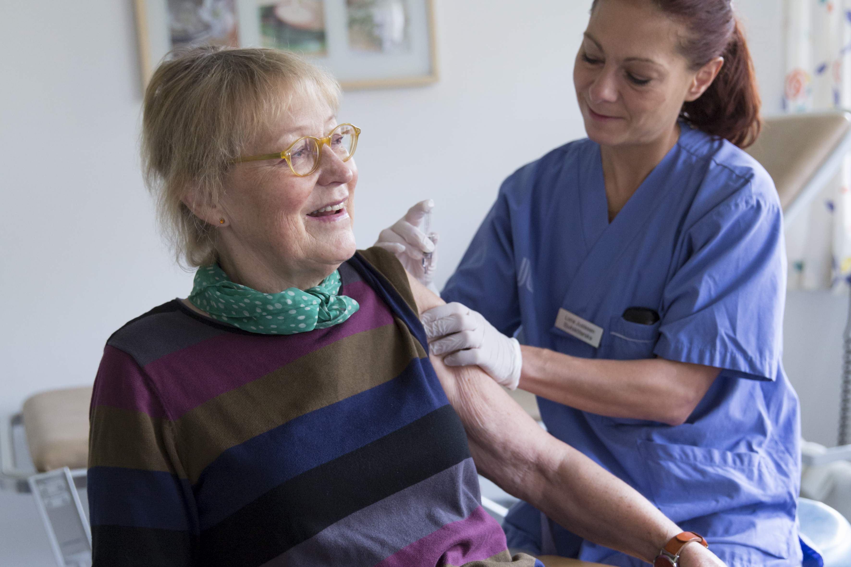 Glad person som får en spruta med vaccin i armen.