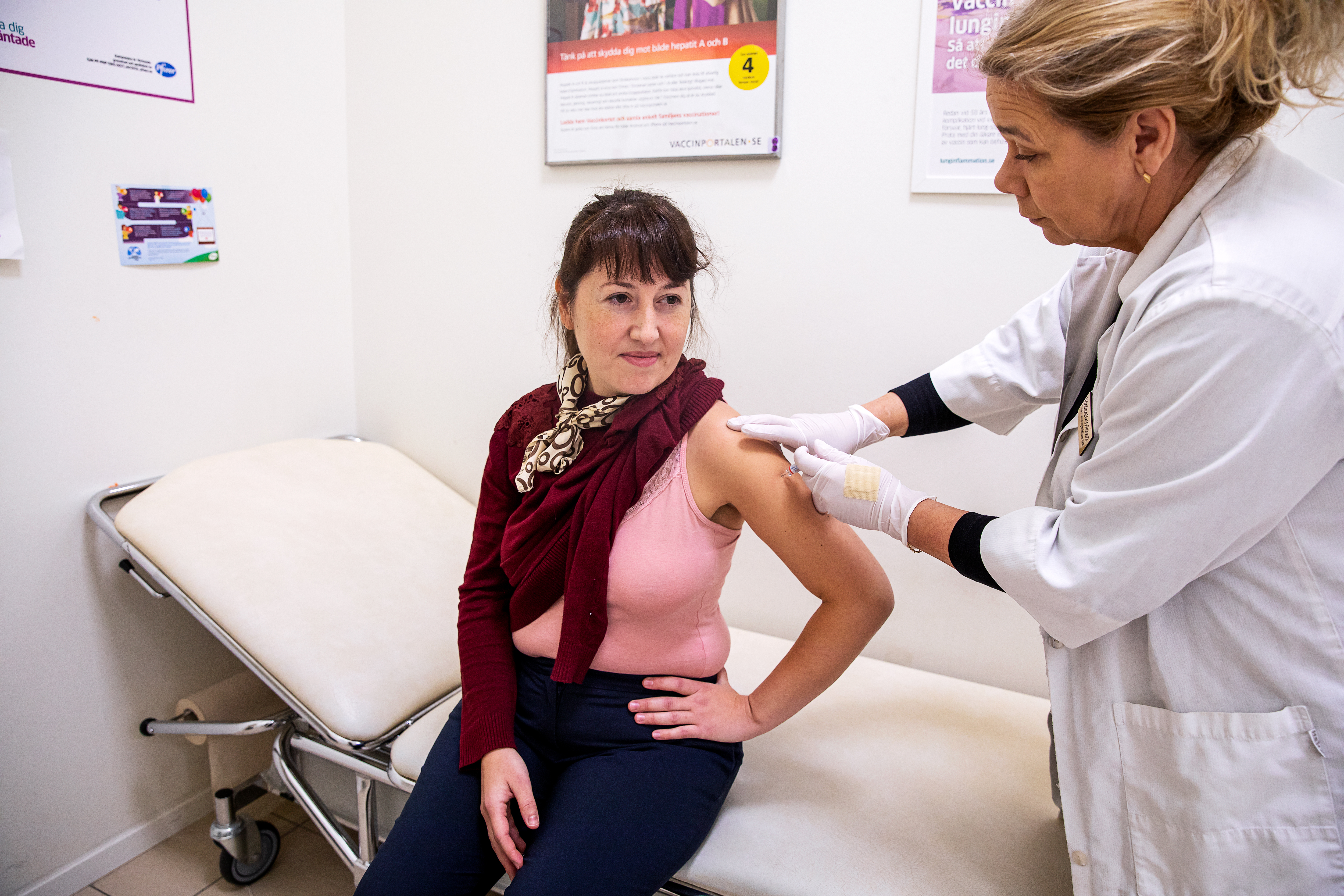 Glad person som får en spruta med vaccin i armen.