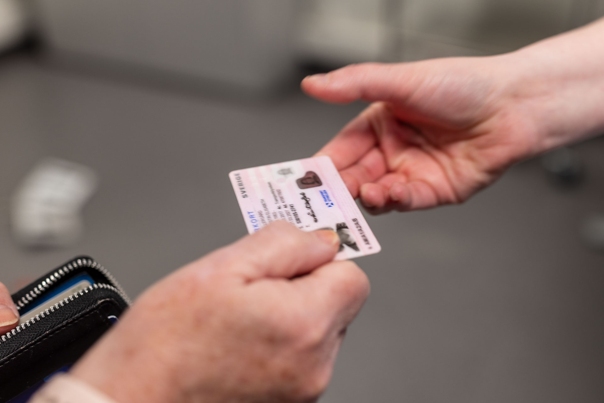 Ett legitimation lämnas från en hand till en annan.