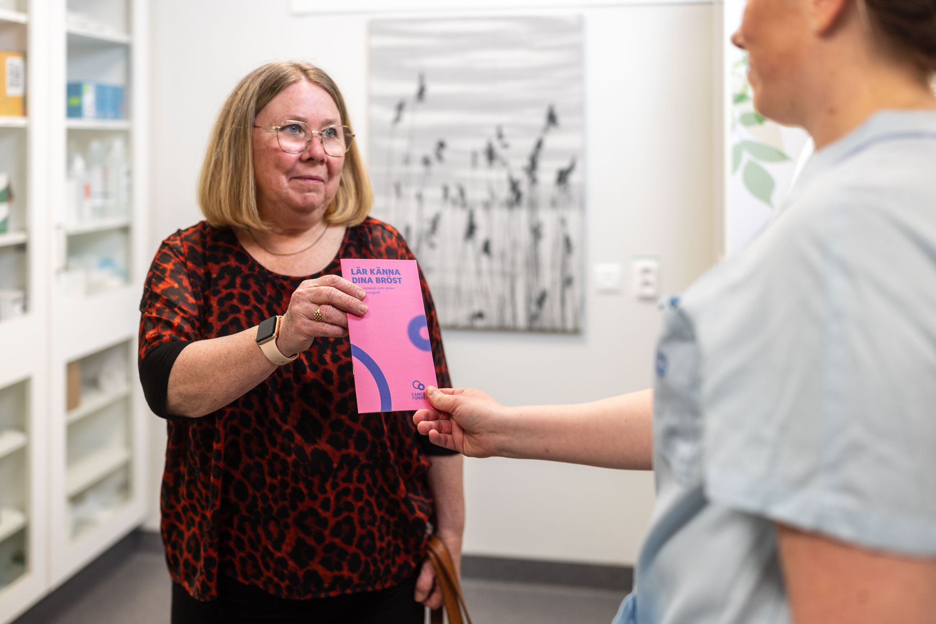 En vårdperson lämnar över en broschyr till en patient.