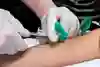 Sjuksköterskan samlar upp blod genom nålen till ett litet rör.