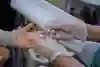 Sjuksköterskan håller ett litet rör mot fingret och samlar upp en bloddroppe.