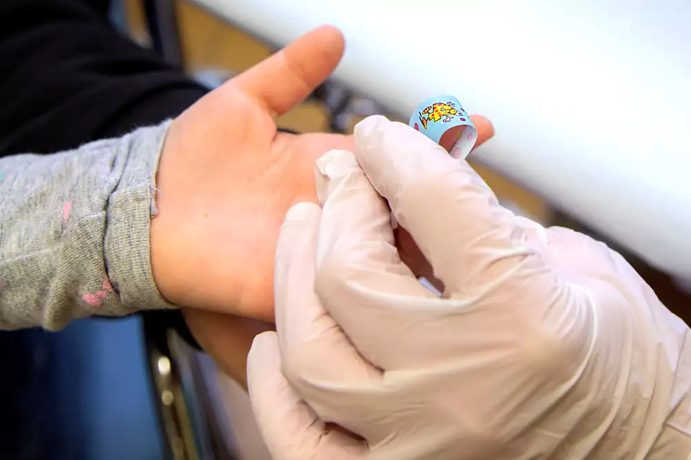 Ett barn med ett plåster på fingret efter ett blodprov.