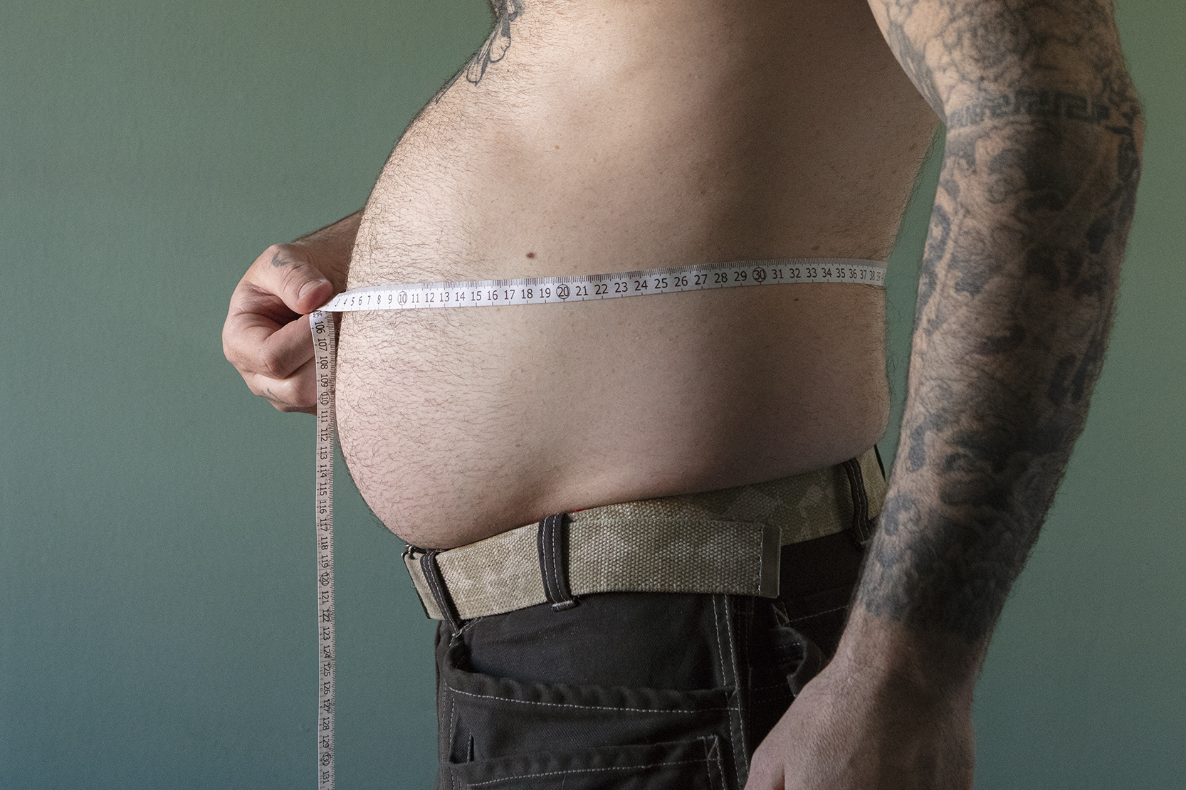 Person som mäter magen med ett måttband. 