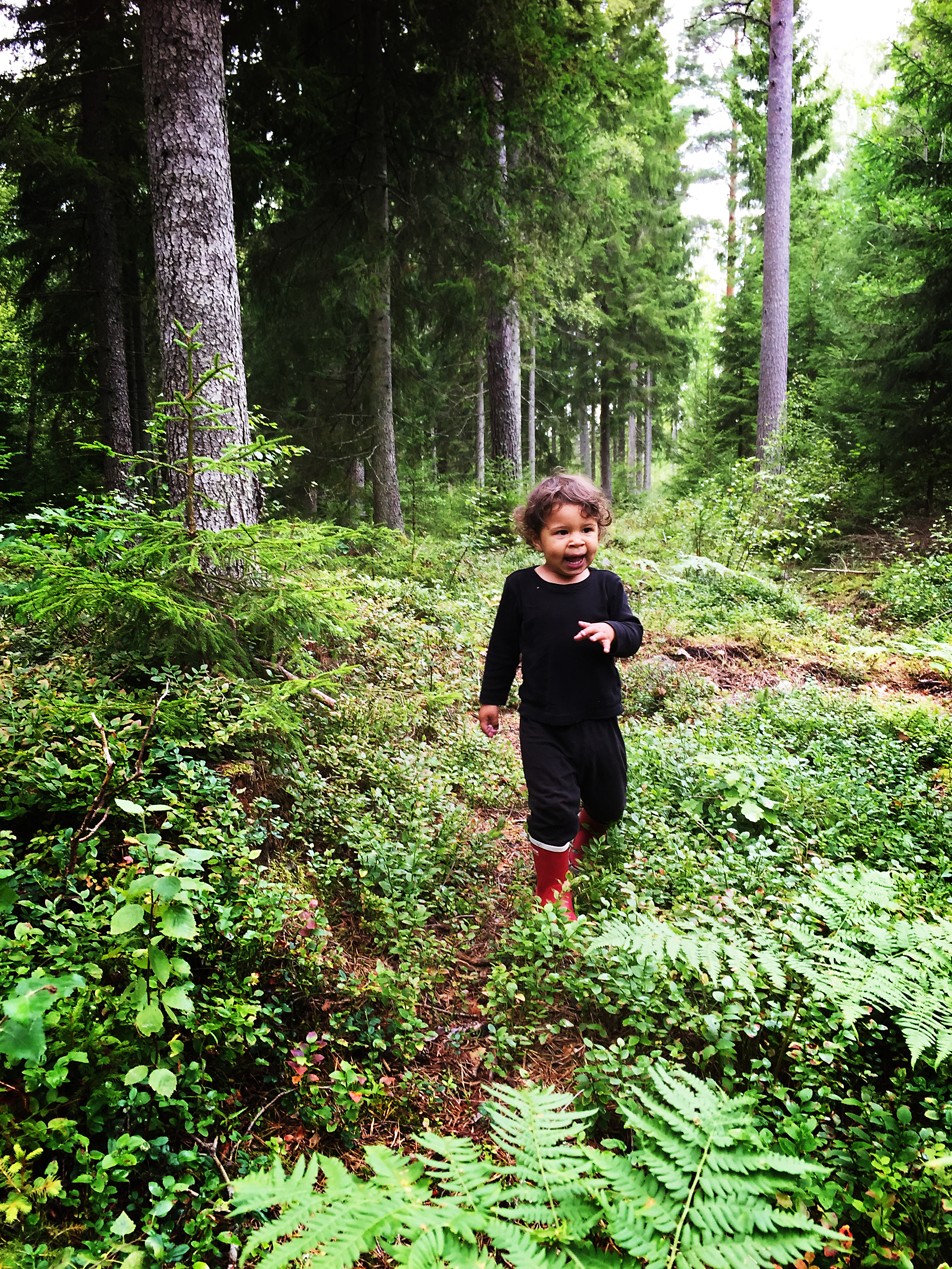 Barn med svarta kläder i skogen. Fotografi. 