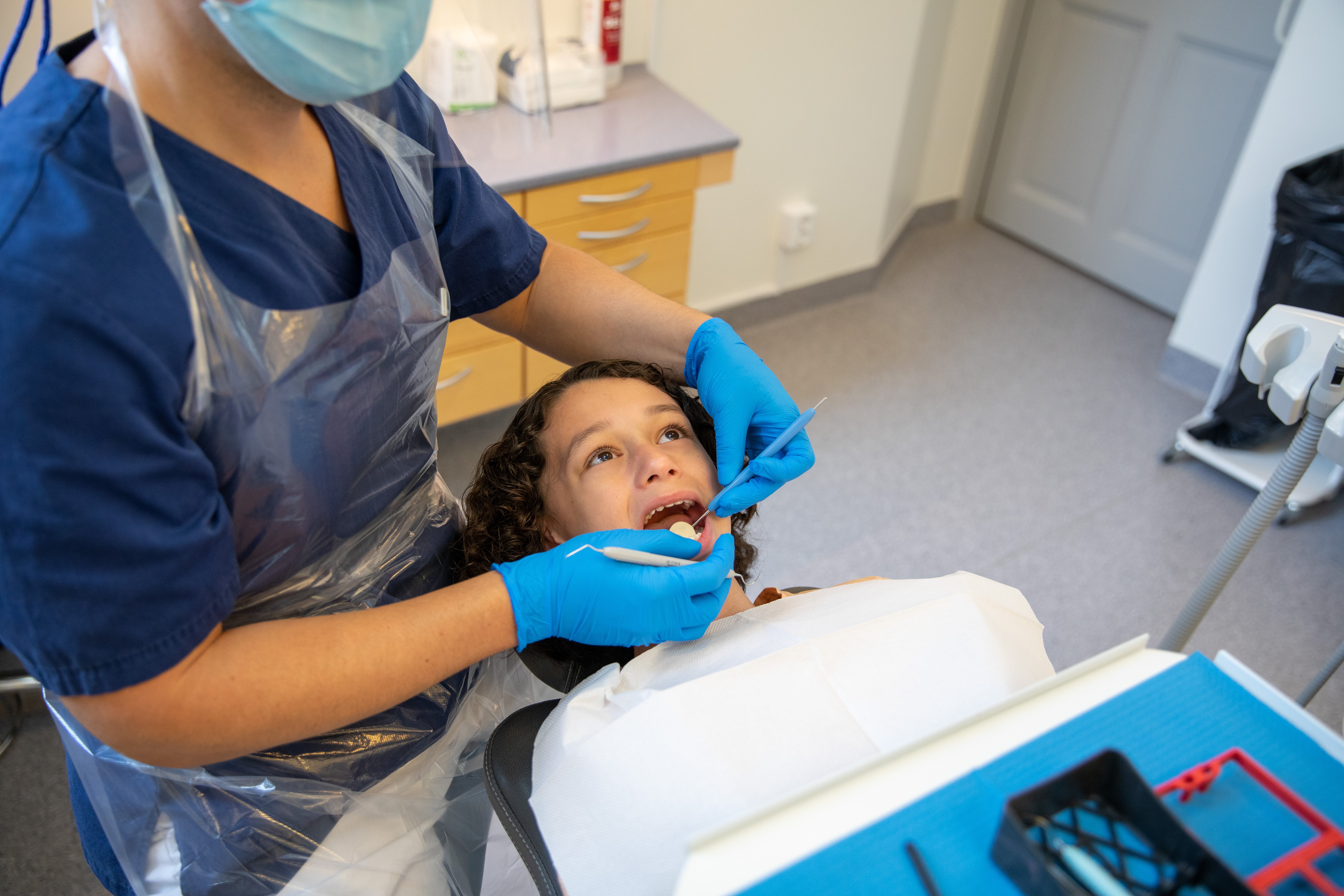 Ett barn i en tandläkarstol som blir undersökt i munnen.