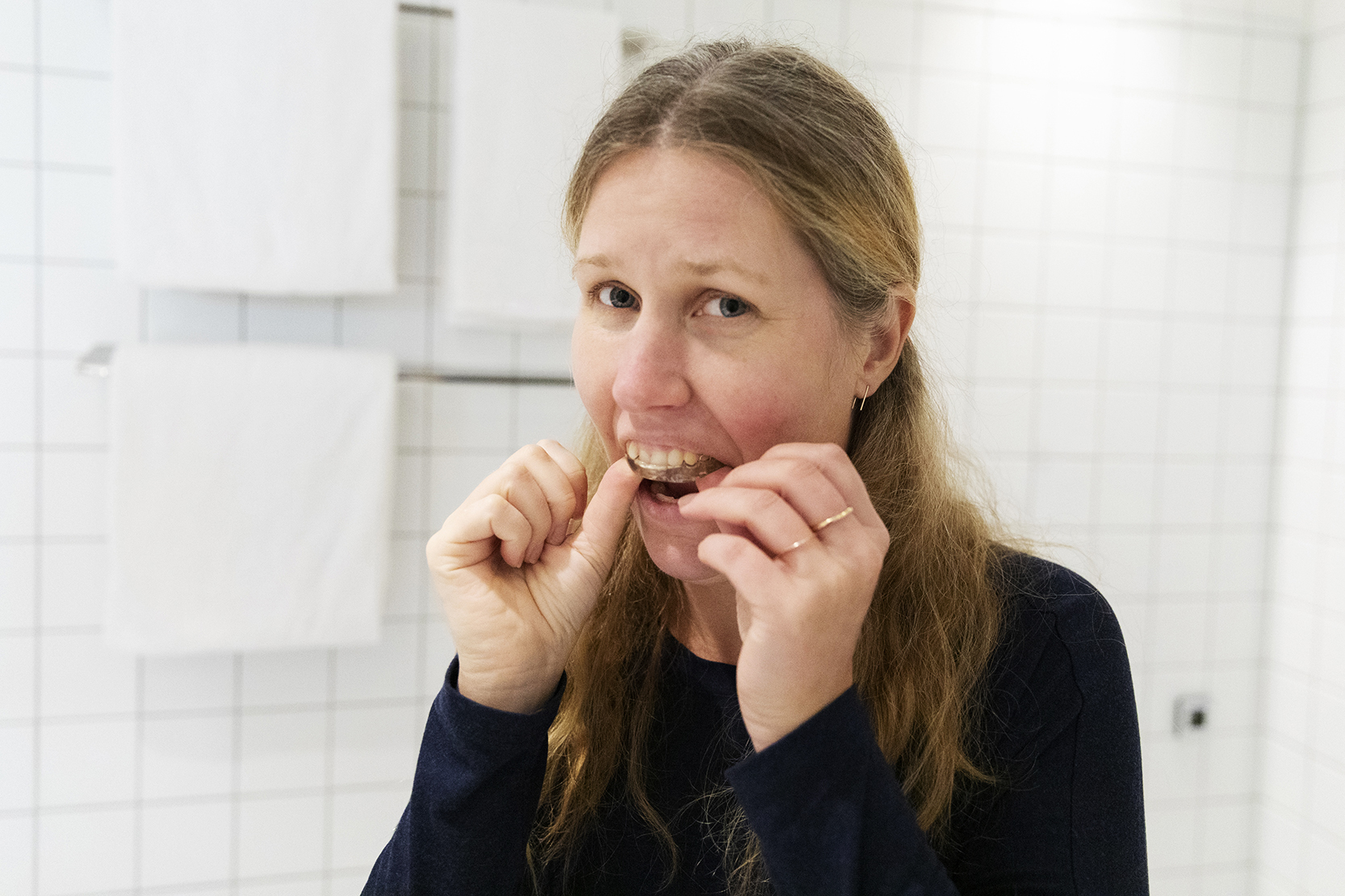 En ung kvinna som sätter in en bettskena i munnen.