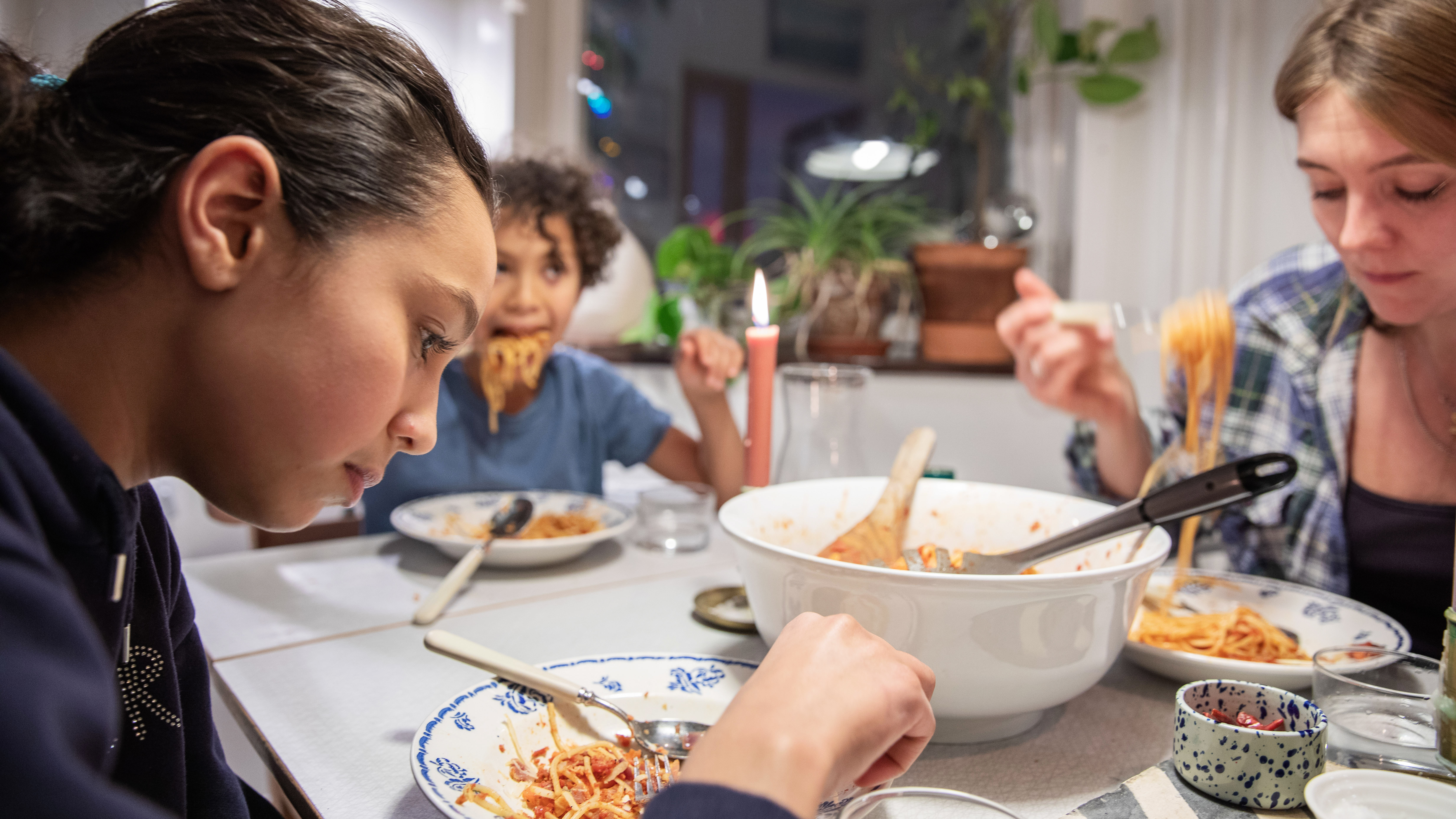 Ett barn tittar allvarligt ner i sin tallrik under en middag med familjen.