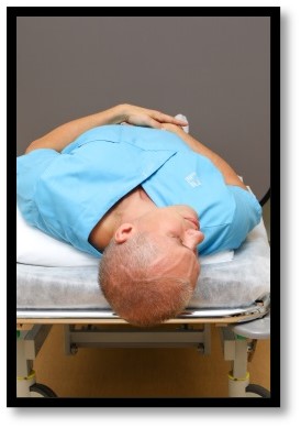 Person ligger med huvudet utanför sängen.