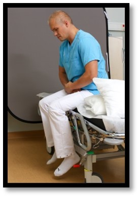 Person sitter på sängkant. 