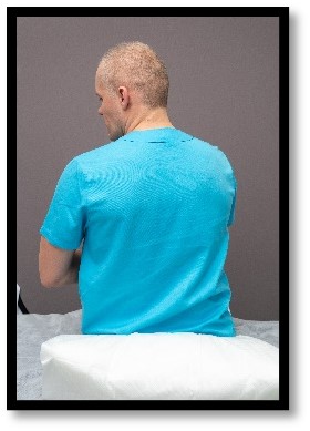 Person sitter på säng med huvudet 45 grader åt vänster.