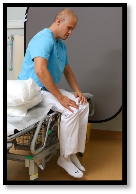 Person sitter upp med huvudet böjt neråt.