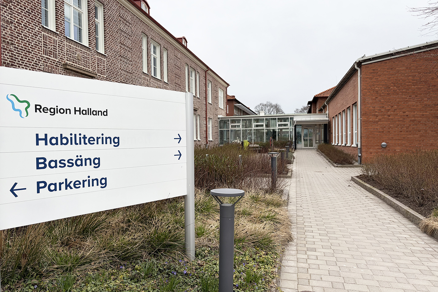 Skylten utanför pekar på entrén till Habiliteringen och till bassängen