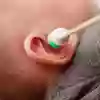 Närbild på ett barns öra med en propp.