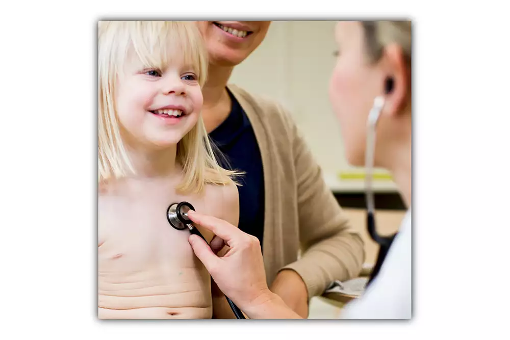 Barnläkare lyssnar på hjärtat med att stetoskop på ett barn.