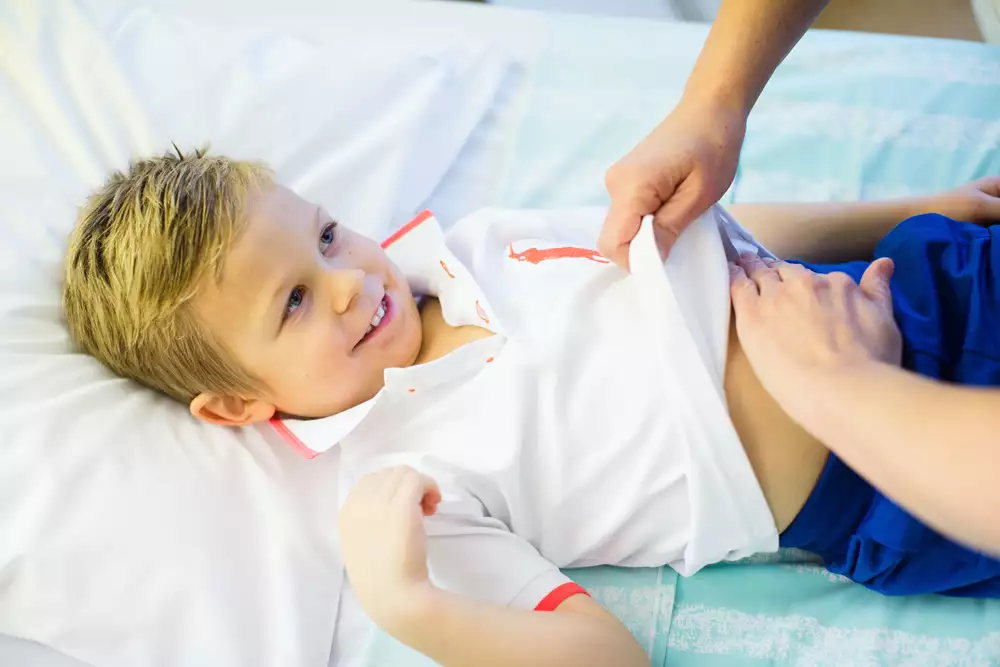 Ett barn undersöks av vårdpersonal som trycker på magen.