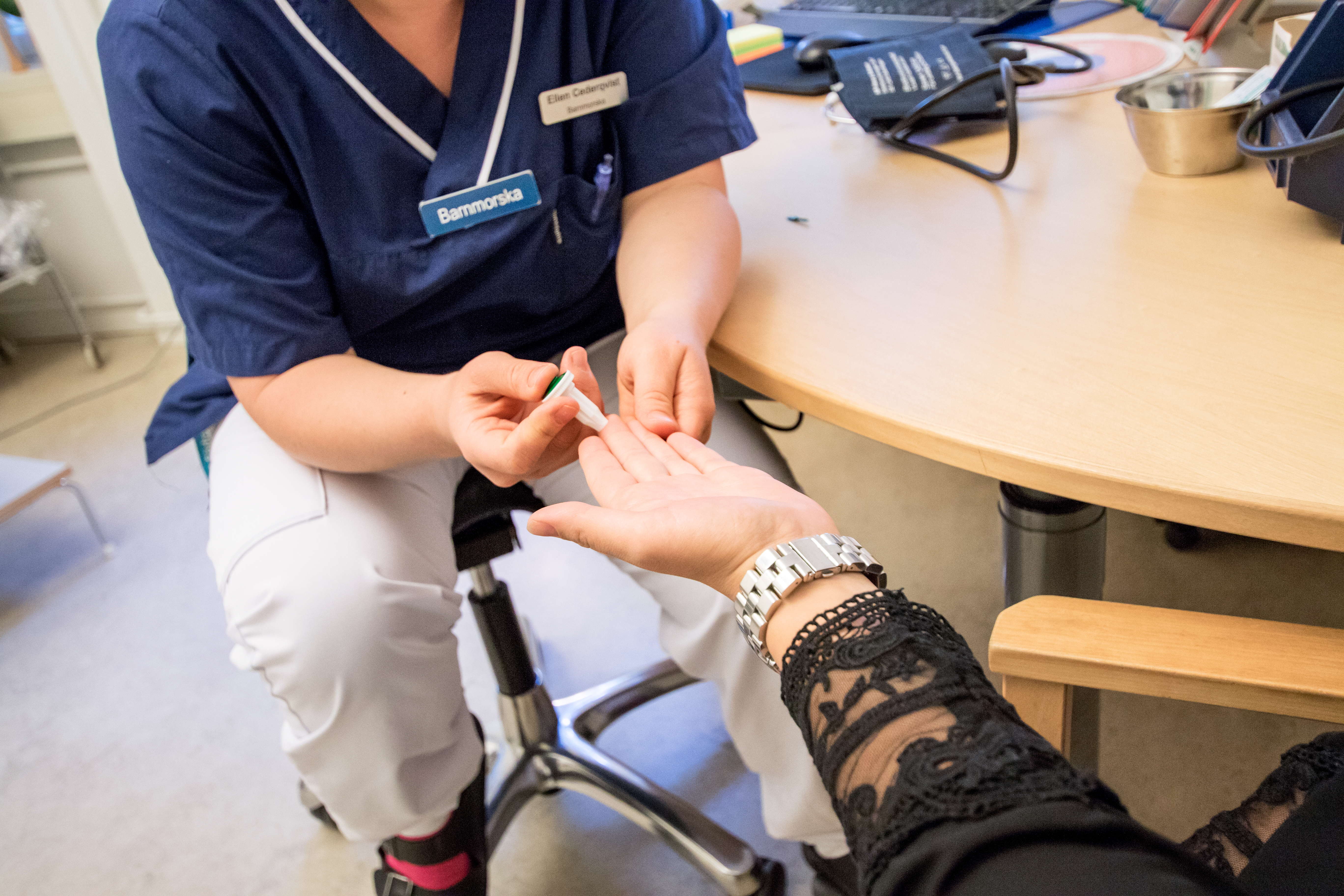 En barnmorska sticker en patient i fingret för att mäta blodsockret..