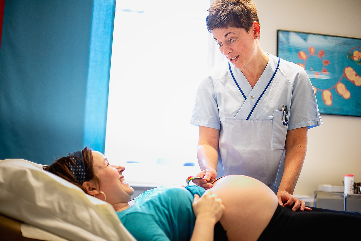 Gravid kvinna får magen mätt av en barnmorska med ett måttband.