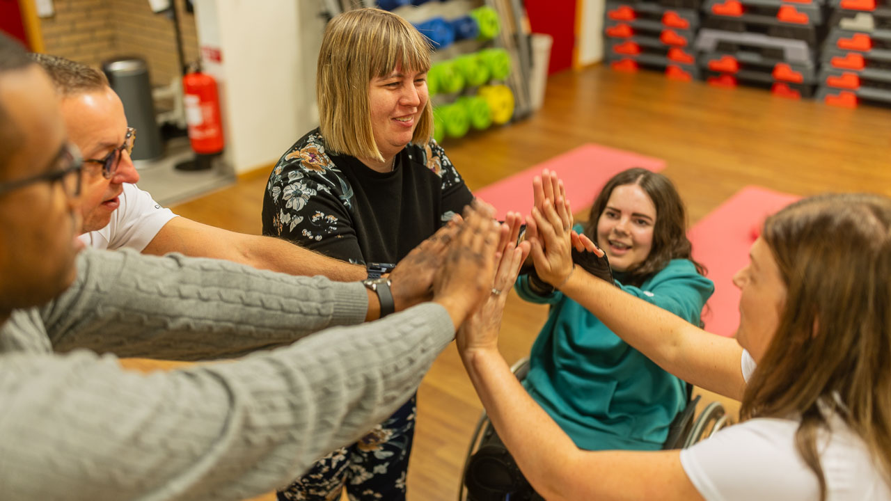 En grupp människor som sitter i en ring med händer in mot mitten.