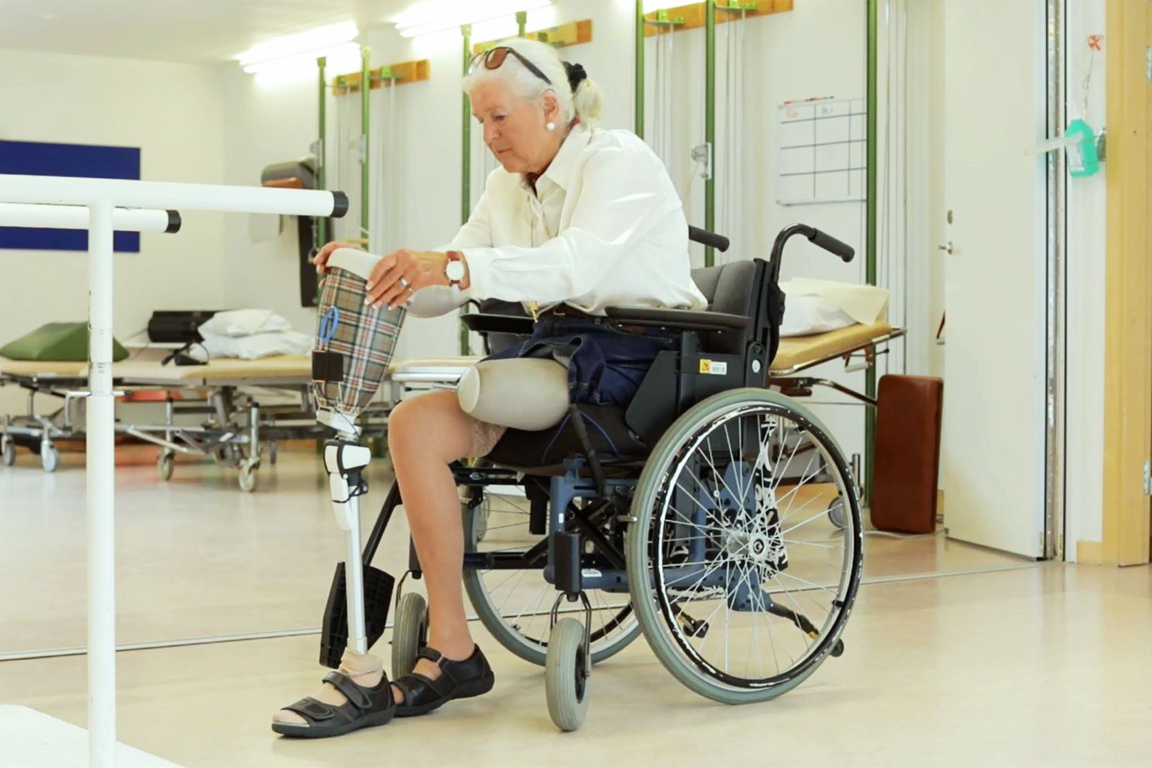 Kvinna i rullstol som trär på sin benprotes
