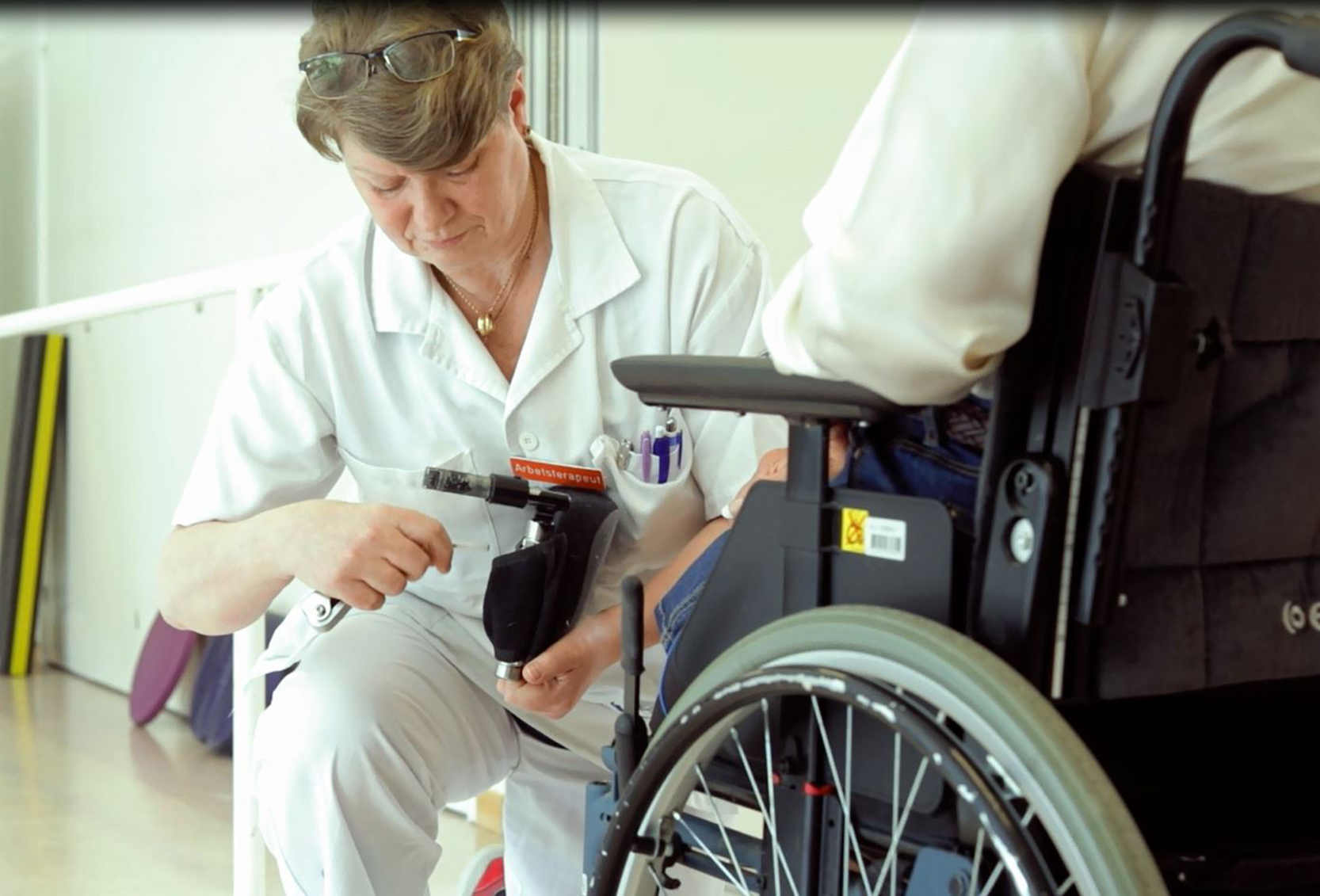 Arbetsterapeut skruvar på hjälpmedel till rullstol
