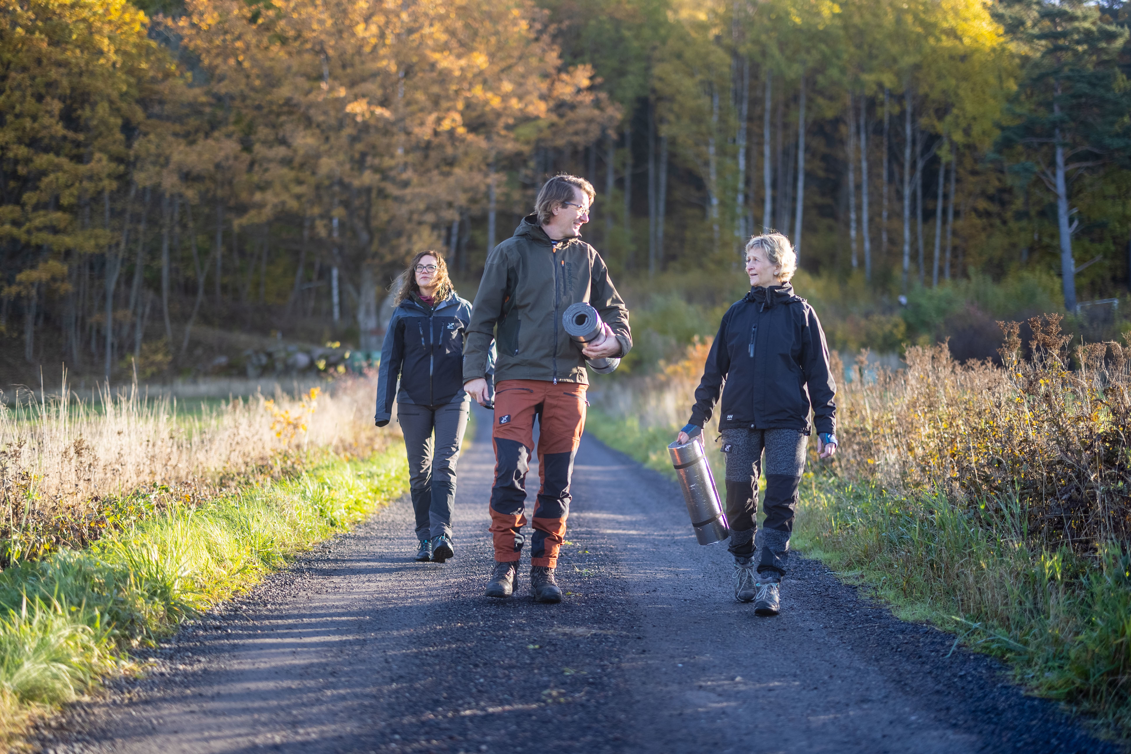 Tre personer går på en grusväg