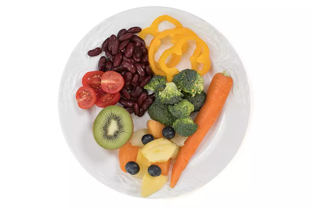 En tallrik med olika grönsaker och frukter, bland annat bönor, paprika, morot, broccoli och kiwi.
