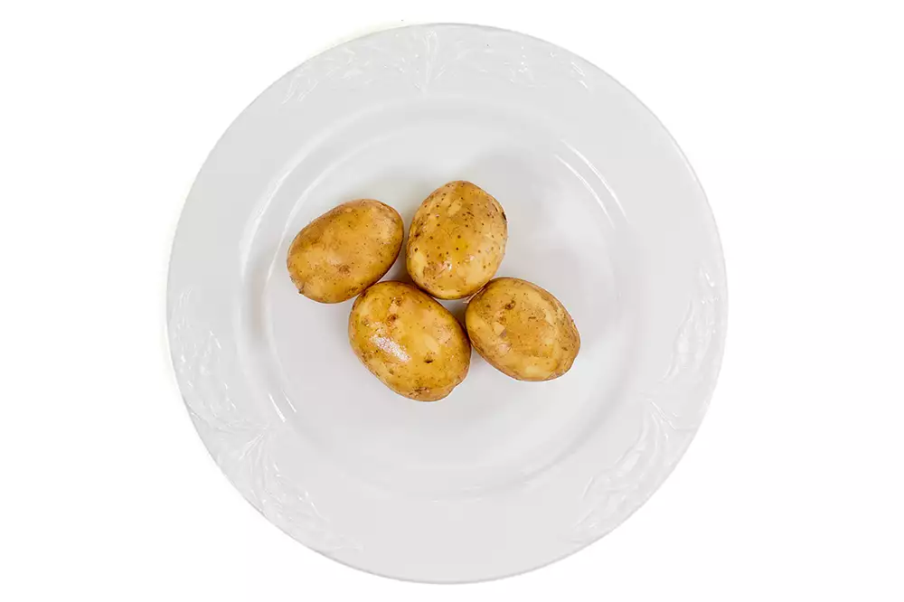 En tallrik med fyra potatisar.
