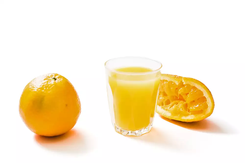 En apelsin och ett glas med apelsinjuice.