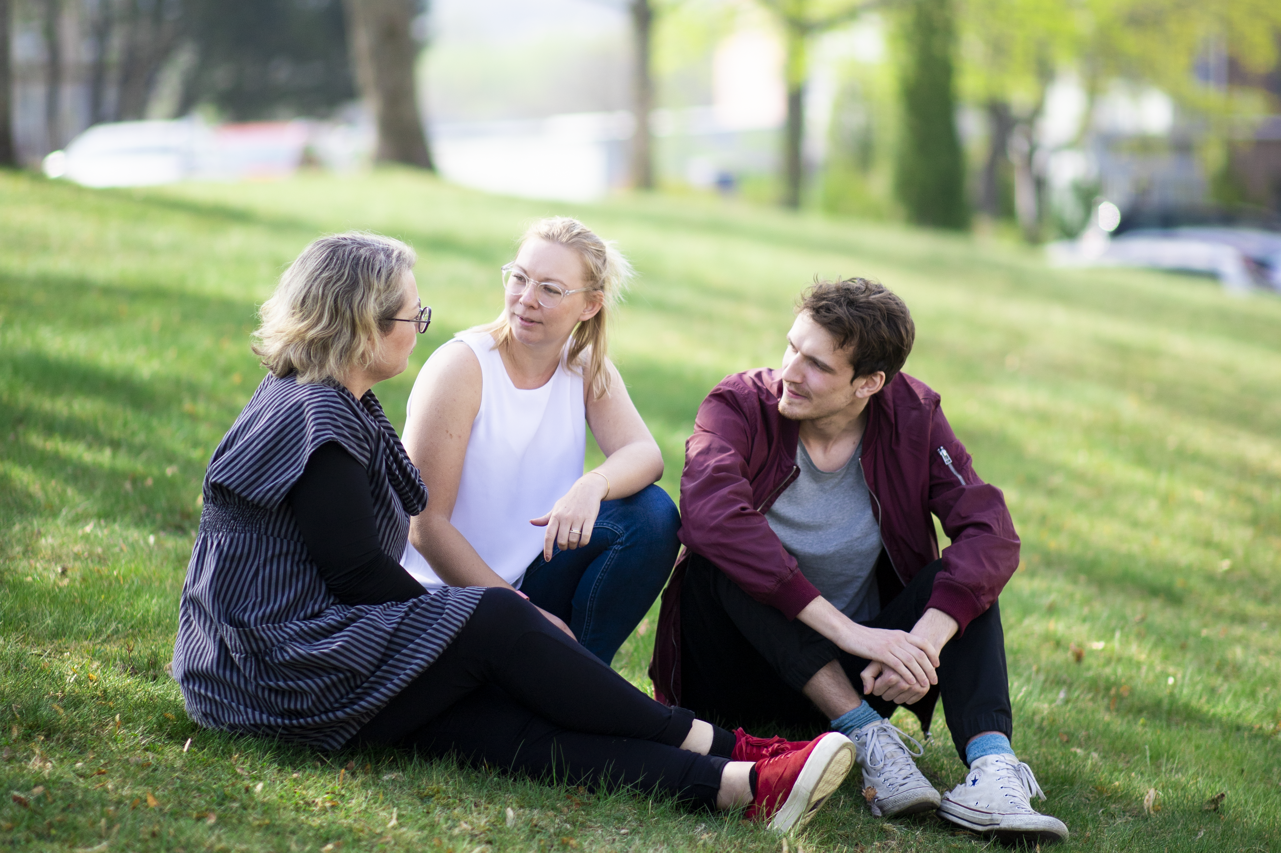 Personer sitter på en grästmatta och pratar