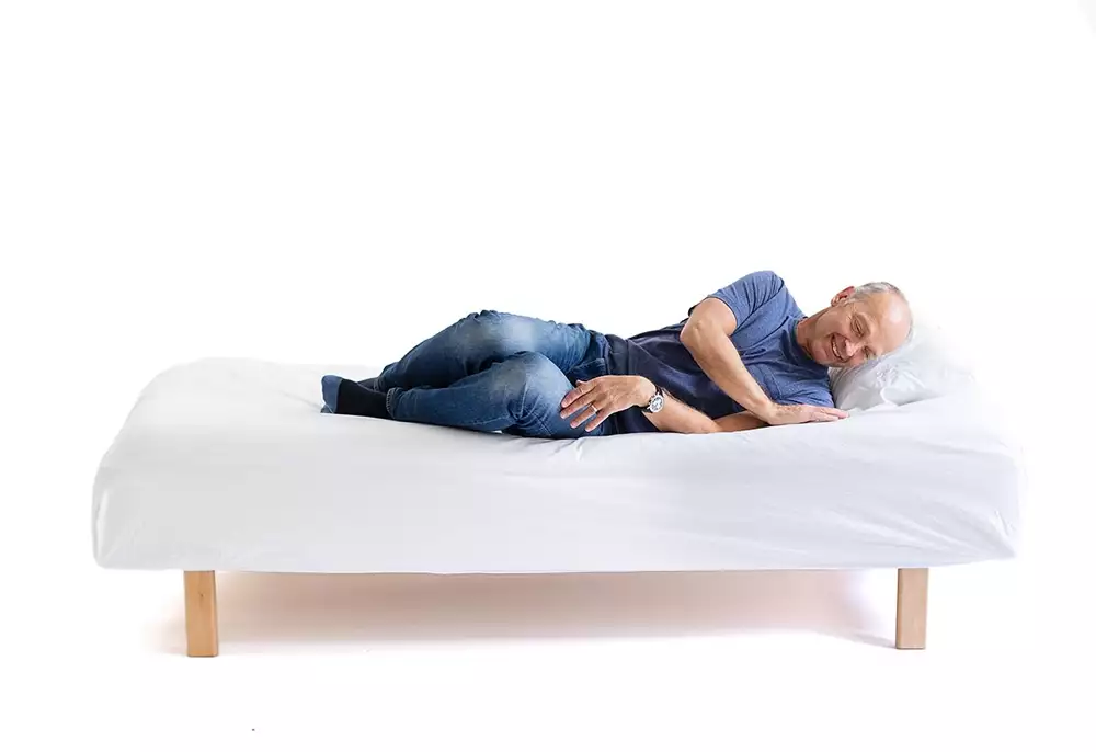 2. Vänd över på sidan och sätt i handen vid axeln. Lägg ut underbenen utanför sängen. 