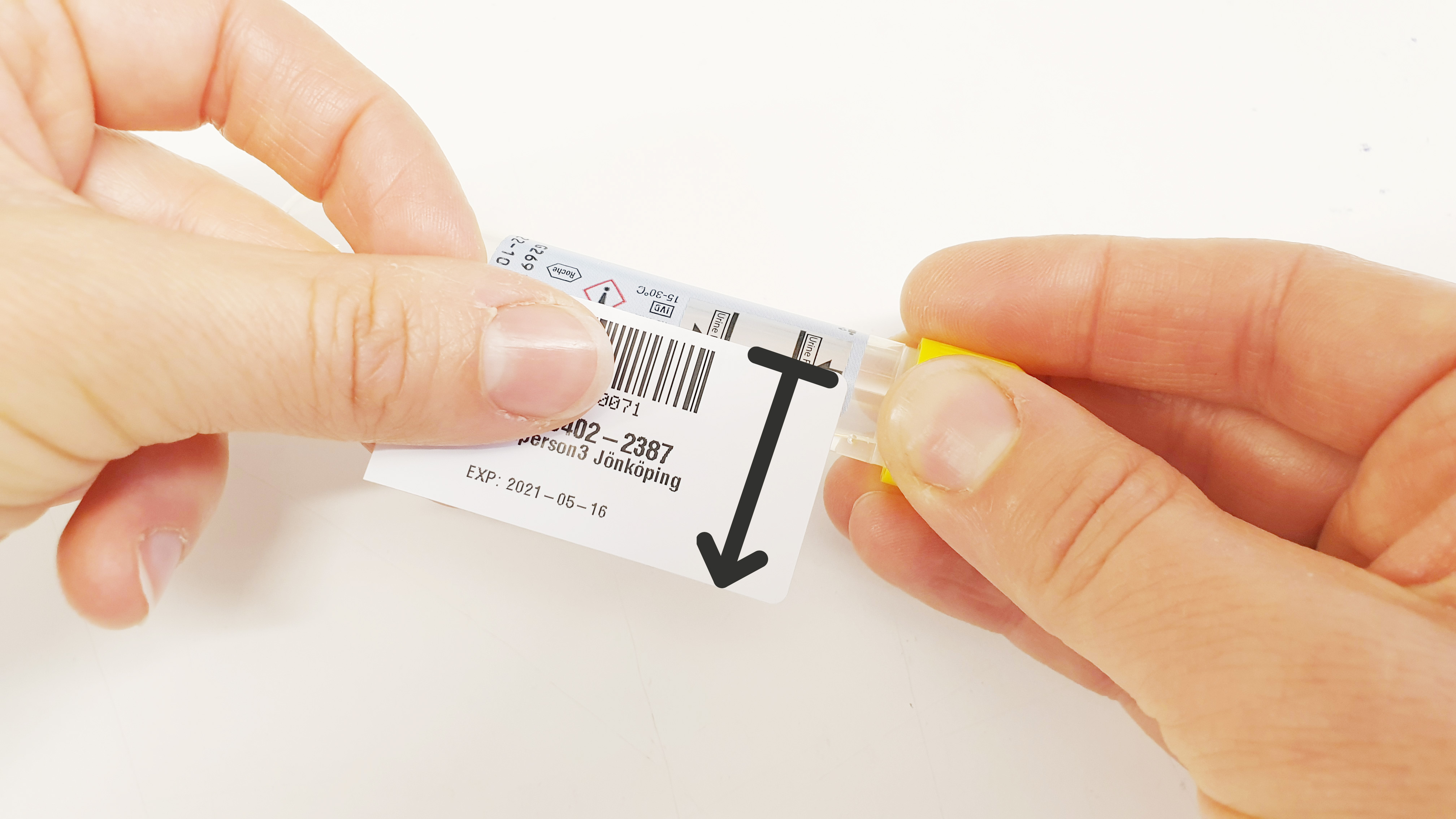 En etikett med streckkod hålls i båda händerna i närbild.