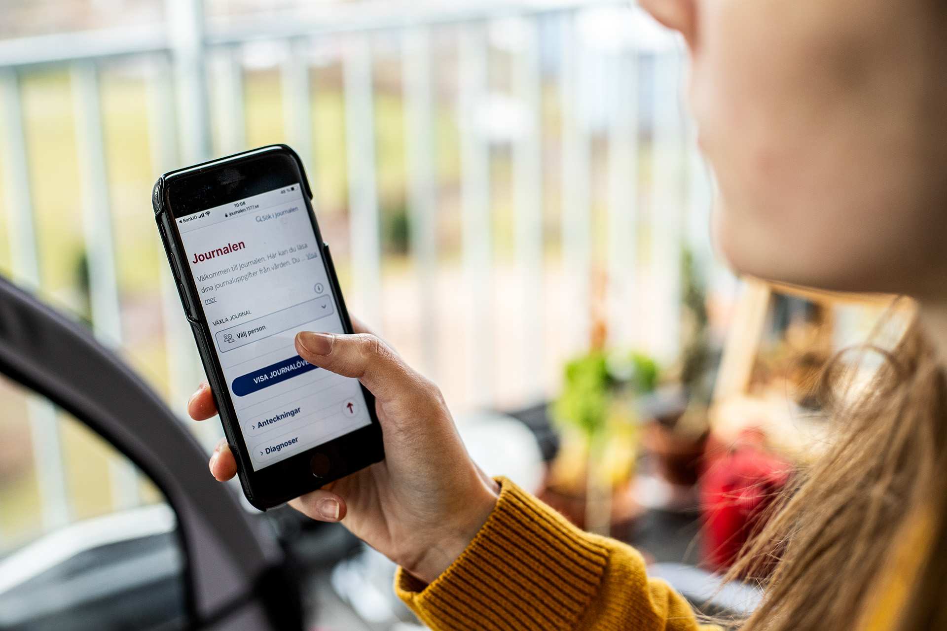 Person håller i en läsplatta och klickar på journalen på 1177.se