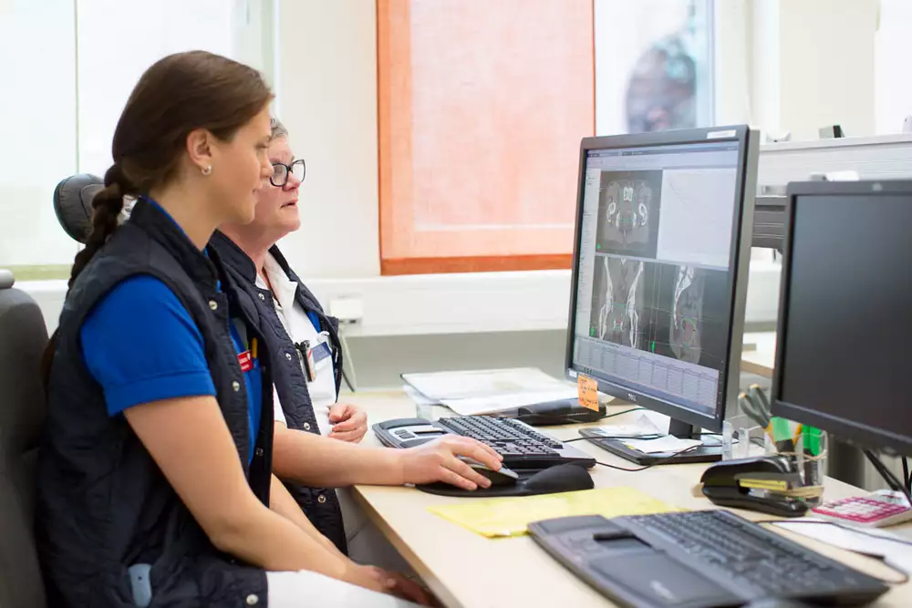 Två vårdpersoner sitter och tittar på en bildskärm med röntgenbilder.